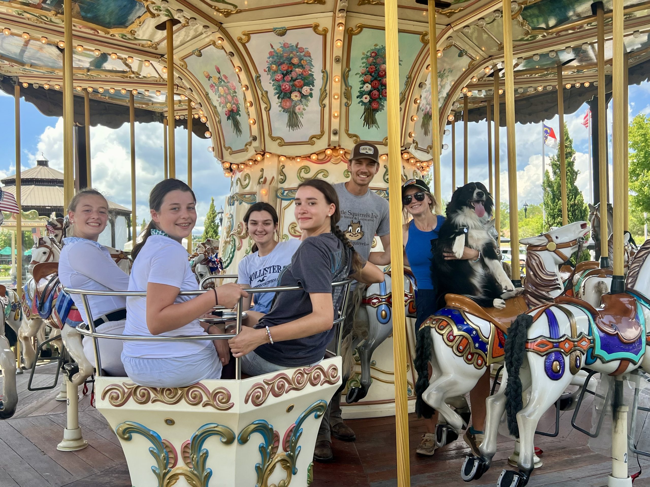 MacNair's show team riders with off-site managers Fern and Luke and their dog Owen on the carousel at Tryon International Equestrian Center